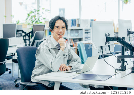 A young man in work clothes working at a company 125821539