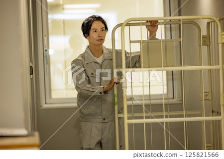 A man wearing work clothes carrying a container 125821566