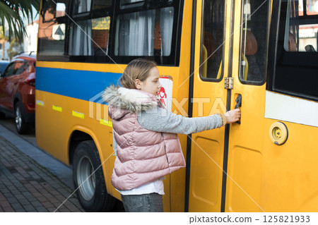 Young girl child school student opens the door of a school bus 125821933