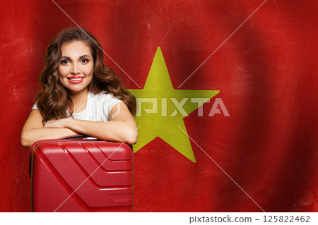Young friendly woman with red suitcase against Vietnamese flag background. Love Vietnam concept. 125822462