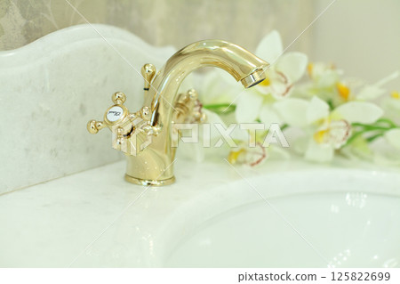 Marble and gold. Golden faucet on stone surface in luxurious bathroom, interior detail 125822699
