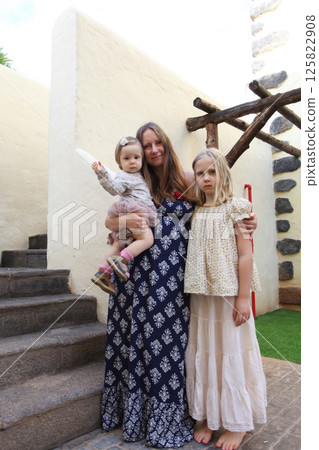 Outdoor portrait of pretty mother and two daughter. Woman, baby one year old and young child girl eight years old 125822908