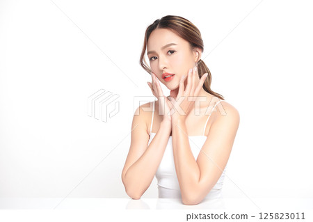 A beautiful young Asian woman with clean, fresh skin against a white background. Skincare, facial treatment, cosmetology, beauty, and spa. An elegant portrait of an Asian woman. 125823011