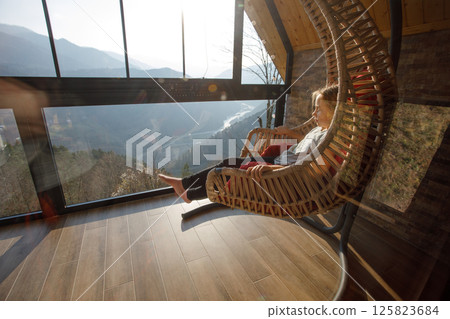 Child girl sitting in the hammock and looking on the mountains in Variaki, Georgia 125823684