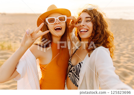 Two pretty friends women making selfie on beach, light and bright summer colors. Friends together Two pretty friends women making selfie on beach, light and bright summer colors. Friends together 125823696