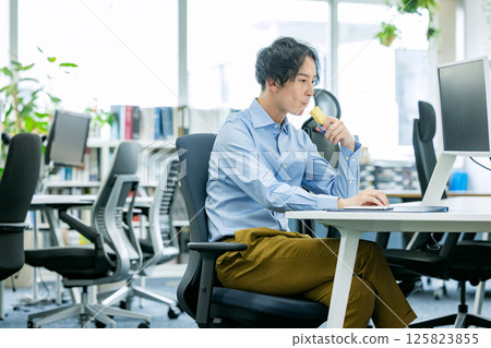 Man eating a protein bar in the office 125823855