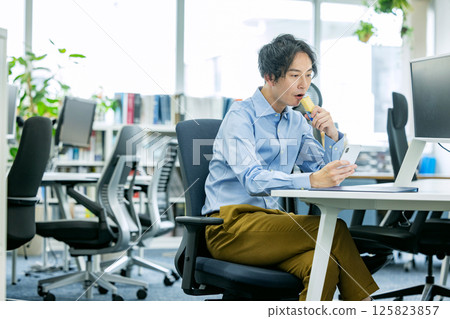 Man eating a protein bar in the office 125823857