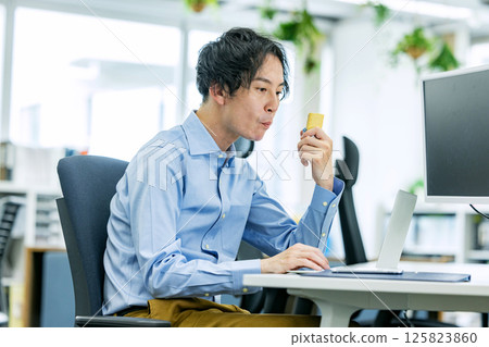 Man eating a protein bar in the office 125823860