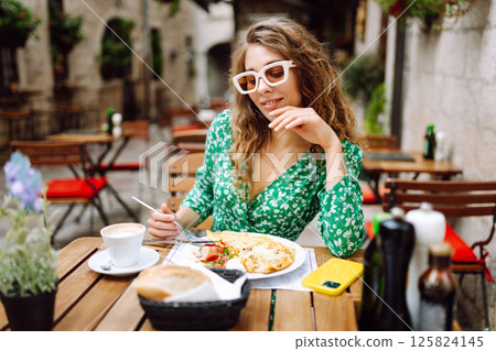 Portrait of a smiling woman eating pasta at cozy Italian restaurant outdoors. 125824145