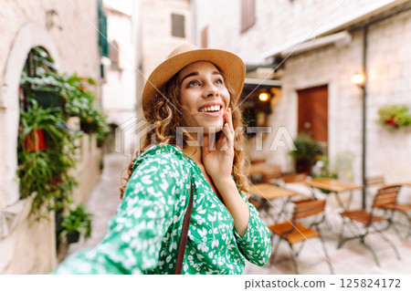 Beautiful woman walks the streets and takes selfie using smartphone camera Beautiful woman walks the streets and takes selfie using smartphone camera 125824172