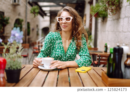 Young woman tourist drinks coffee in the old town in summer trip. People, fashion, lifestyle Young woman tourist drinks coffee in the old town in summer trip. People, fashion, lifestyle 125824173