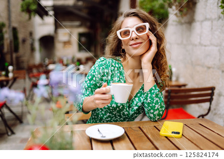 Young woman tourist drinks coffee in the old town in summer trip. People, fashion, lifestyle Young woman tourist drinks coffee in the old town in summer trip. People, fashion, lifestyle 125824174