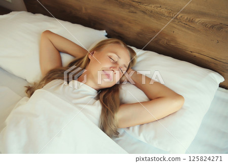 Woman sleeping lying in bed on white soft comfortable pillow in bedroom at home Woman sleeping lying in bed on white soft comfortable pillow in bedroom at home 125824271