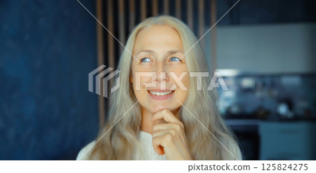 Pensive mature woman thinks looking out the window in living room with kitchen at home 125824275