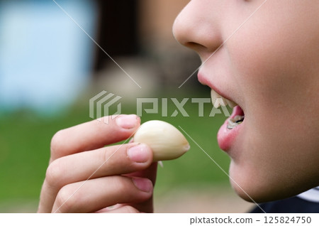 Child about to eat a clove of garlic 125824750