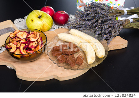Assortment of fruits, snacks, and dried lavender on a wooden board. 125824824