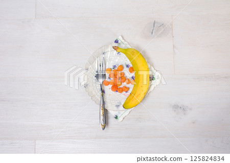 Banana and berries on a plate with a fork. Banana and berries on a plate with a fork. 125824834