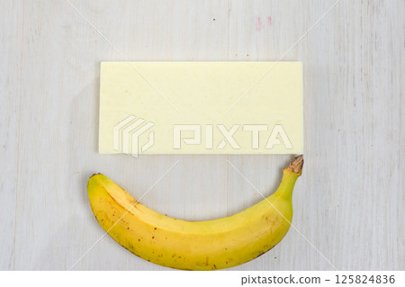 Ripe banana and a block of white material on a wooden surface. Ripe banana and a block of white material on a wooden surface. 125824836