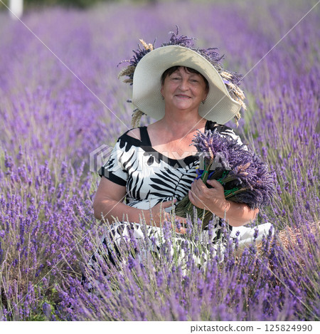 Woman in a lavender field holding a bouquet of lavender. Woman in a lavender field holding a bouquet of lavender. 125824990