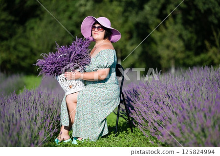 Woman in a lavender field, holding a basket of freshly picked lavender. Woman in a lavender field, holding a basket of freshly picked lavender. 125824994