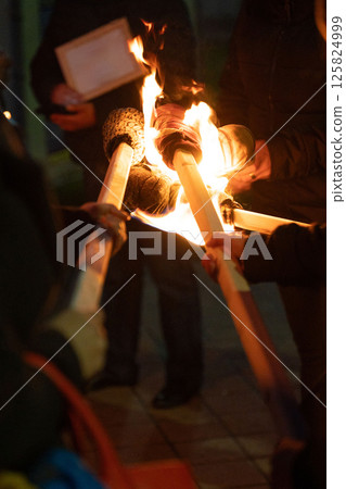 People hold burning torches in a nighttime gathering. 125824999