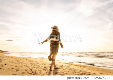 Carefree woman relaxing on coast at sunset. Windy autumn days. The concept of relaxation Carefree woman relaxing on coast at sunset. Windy autumn days. The concept of relaxation 125825222