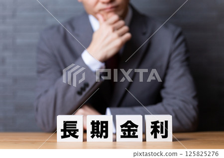 A middle-aged male businessman wearing a suit and worried about the block of long-term interest rates 125825276