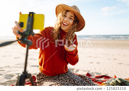 Happy woman using smartphone with stabilizer, live video in on sea beach. Live session blogging. Happy woman using smartphone with stabilizer, live video in on sea beach. Live session blogging. 125825318