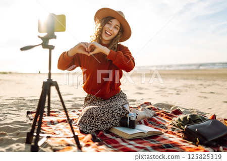 Happy woman using smartphone with stabilizer, live video in on sea beach. Live session blogging. Happy woman using smartphone with stabilizer, live video in on sea beach. Live session blogging. 125825319
