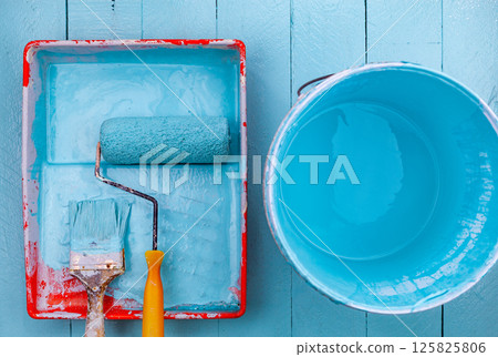 Paint brush in color tray and paint bucket,White glove on blue wooden background 125825806
