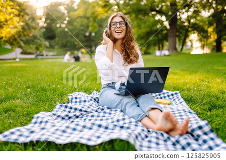 Young woman headphones sits listen to music use mobile cell phone. Concept for business, freelance. Young woman headphones sits listen to music use mobile cell phone. Concept for business, freelance. 125825905