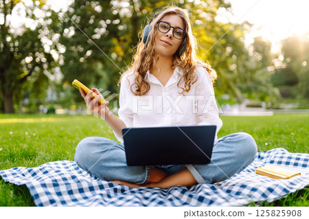 Young woman headphones sits listen to music use mobile cell phone. Concept for business, freelance. 125825908