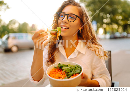 Young tourist standing in the middle of the street, eating takeaway lunch while taking in the sights Young tourist standing in the middle of the street, eating takeaway lunch while taking in the sights 125825924