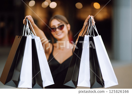 Shopping bags in the hands. Fashion woman with packages after shopping. Black friday, sale. 125826166