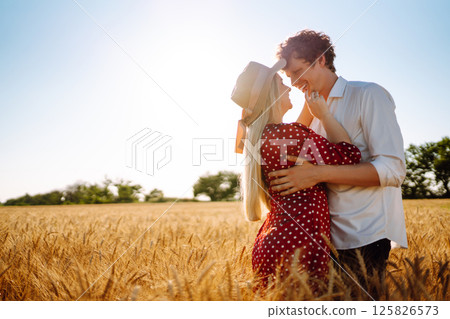 Young happy couple hugging on a wheat field, on the sunset. Enjoying time together. Young happy couple hugging on a wheat field, on the sunset. Enjoying time together. 125826573