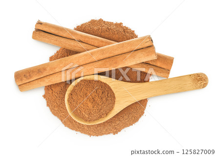 Cinnamon sticks with powder in wooden spoon isolated on white background. Top view. Flat lay. 125827009