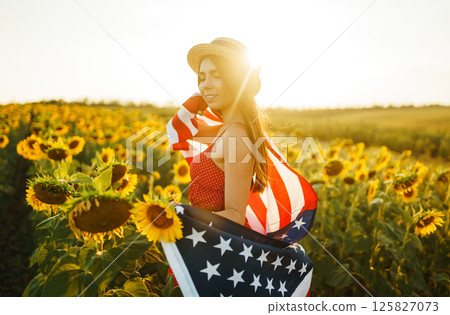Beautiful girl in hat with the American flag in a sunflower field. 4th of July. Fourth of July. Independence Day. Beautiful girl in hat with the American flag in a sunflower field. 4th of July. Fourth of July. Independence Day. 125827073