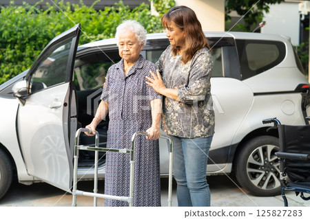 Caregiver help Asian elderly woman disability patient get in her car. Caregiver help Asian elderly woman disability patient get in her car. 125827283