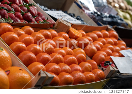Fresh mandarin oranges in boxes at food market. Boxes of tangerines among other fruits and berries on the counter of a food market Fresh mandarin oranges in boxes at food market. Boxes of tangerines among other fruits and berries on the counter of a food market 125827547