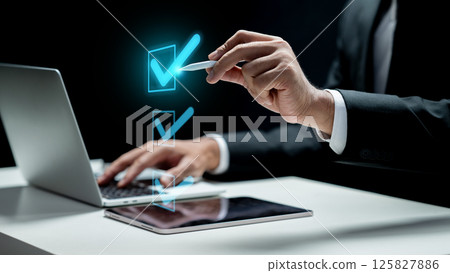 Businessman with laptop touching icon of check mark list on tablet screen. Technology innovation on a virtual screen. Concept of Compliance 125827886