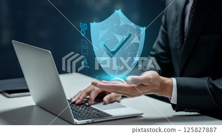 Businessman with laptop showing checkmark on wireframe shield on his hand. Technology innovation on a virtual screen. Concept of Compliance 125827887