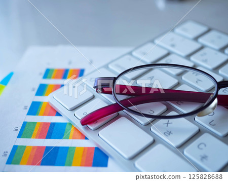 Graph, keyboard and glasses on a table 125828688