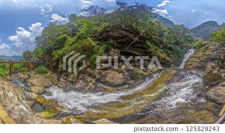 The tall Diyaluma waterfall cascades down a steep rocky slope in lush Sri Lankan highlands The tall Diyaluma waterfall cascades down a steep rocky slope in lush Sri Lankan highlands 125829243