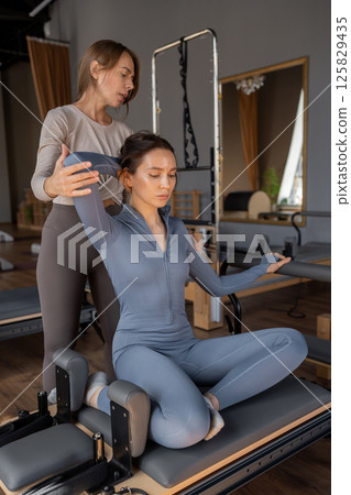 Woman doing mermaid exercise in a sunlite, modern pilates studio, embodying calm, focus, and strength. 125829435