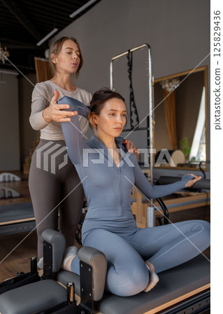 Woman doing mermaid exercise in a sunlite, modern pilates studio, embodying calm, focus, and strength. 125829436