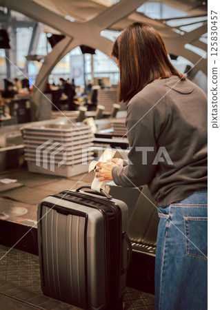 Female putting her luggage on weight at check in counter at airport. 125830457
