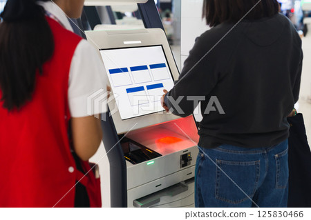 Woman at self service transfer area doing self check in at airport. Woman at self service transfer area doing self check in at airport. 125830466