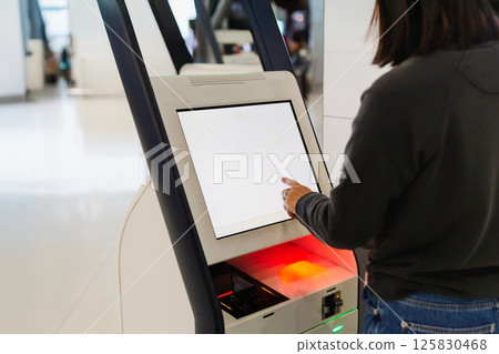 Woman at self service transfer area doing self check in at airport. 125830468