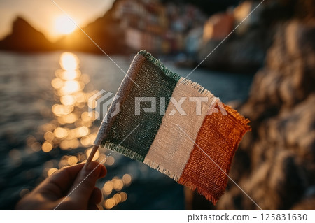 Hand holding Italy flag at sunset by the sea 125831630
