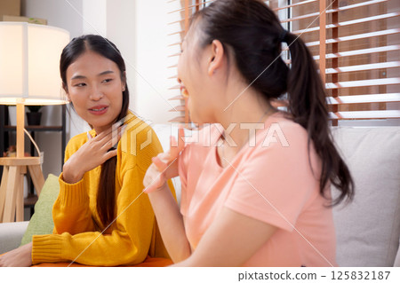 Two friends conversation and sitting on sofa in cozy living room at home, gossip with friends. Two friends conversation and sitting on sofa in cozy living room at home, gossip with friends. 125832187
